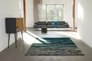 Designteppich 'Shallow Water' von Hamann & Hilzinger – strukturiertes blau‑graues Wellenmuster