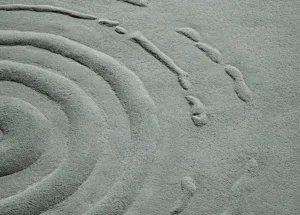 Ein Teppich, der einen Wassertropfen auf einer glatten Fläche wiederspiegelt.